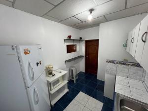 a kitchen with a white refrigerator and a blue tile floor at Hospedaje El Descanso CERCA CONSULADO AMERICANO GUAYQUIL in Guayaquil
