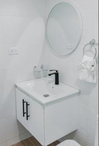 uma casa de banho branca com um lavatório e um espelho em Helios luxurious condo at Caleta em La Romana
