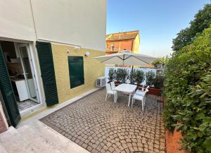 een terras met een tafel, stoelen en een parasol bij Green House Camerano in Camerano