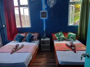 2 camas en una habitación con paredes y ventanas azules en Chez Tonio Magic Ocean View en Rodrigues Island