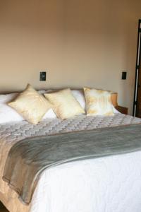 a large white bed with five pillows on it at Pousada e Vinícola Boutique Bégamo - Vale dos vinhedos in Bento Gonçalves