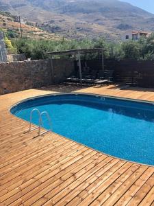 a swimming pool on a wooden deck next to a house at Villa Jazmin in Marioú