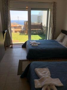 two beds in a room with a large window at Villa Jazmin in Marioú