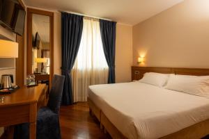 a bedroom with a bed and a desk and a window at Hotel Iris in Genoa