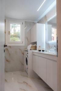 a white kitchen with a sink and a washing machine at Swell Oinousses Apartments in Oinoússai +26 photos