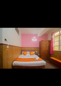 甘托克的住宿－Hotel Yatung，一间卧室配有一张带橙色枕头的大床
