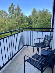- deux chaises sur un balcon avec vue sur les arbres dans l'établissement Apartament 'Wszędzie Blisko', à Kołobrzeg