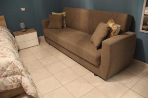 un divano marrone con cuscini in una camera da letto di B&B Sud e Magia a Castelmezzano