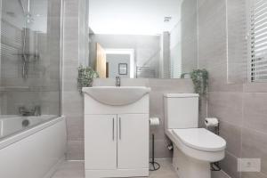 a bathroom with a sink and a toilet and a tub at Lovely 2-Bedroom Bungalow Sleeps 6 with Garden and Off Road Parking by Amazing Spaces Relocations Ltd in Crank