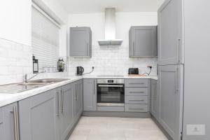 a white kitchen with a sink and a refrigerator at Lovely 2-Bedroom Bungalow Sleeps 6 with Garden and Off Road Parking by Amazing Spaces Relocations Ltd in Crank