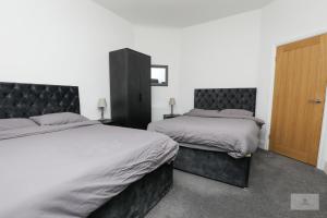 a bedroom with two beds and a wooden door at Lovely 2-Bedroom Bungalow Sleeps 6 with Garden and Off Road Parking by Amazing Spaces Relocations Ltd in Crank