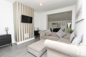 a living room with a white couch and a tv at Lovely 2-Bedroom Bungalow Sleeps 6 with Garden and Off Road Parking by Amazing Spaces Relocations Ltd in Crank