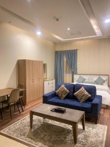 - un salon avec un canapé bleu et un lit dans l'établissement Rose Park Riyadh, à Riyad