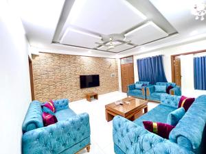 a living room with blue couches and a tv at LUXURY HOTEL E11 in Islamabad