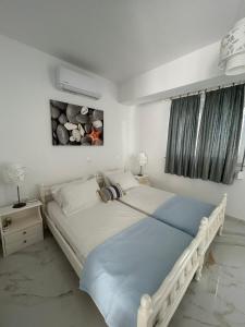 a white bedroom with a large bed and a painting on the wall at Maria's Apartments in Pigi