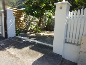 an entrance to a white fence with a gate at Les Palmiers in Saint-Denis