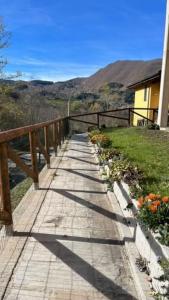 a wooden walkway leading to a house with flowers at APPARTAMENTO RIO ACQUICCIOLA in Fiumalbo