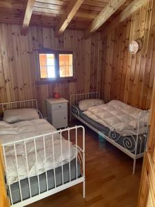 2 Betten in einem Zimmer mit Holzwänden in der Unterkunft Chalet Stickie by Swiss Alps Village in Hérémence