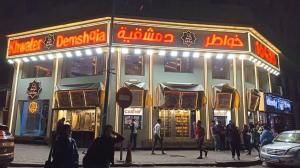 een groep mensen die voor een restaurant staan bij night holiday in Alexandrië