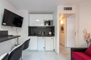 eine Küche mit weißen Schränken und einem roten Sofa in der Unterkunft Le Coquillage - 200 mètres de la Plage in Cannes