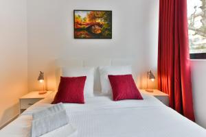 ein Schlafzimmer mit einem weißen Bett mit zwei roten Kissen in der Unterkunft Le Coquillage - 200 mètres de la Plage in Cannes + 9 Fotos
