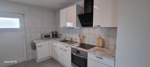 uma cozinha com armários brancos e um lavatório em Ferienwohnung Elefanten em Balingen