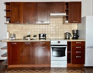 La cuisine est équipée de placards en bois et d'une cuisinière blanche. dans l'établissement Apartament 'Wszędzie Blisko', à Kołobrzeg