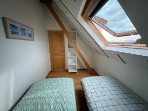 een zolderkamer met een bed en een raam bij La maison du bon air in Wimereux