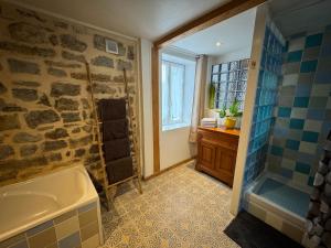 a bathroom with a bath tub and a stone wall at La maison du bon air in Wimereux