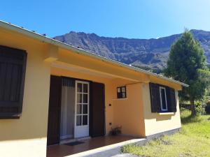 a small yellow house with mountains in the background at Le Zarlor à Cilaos in Cilaos