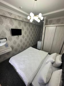 sypialnia z białym łóżkiem i telewizorem w obiekcie IMAM AZAM HOTEL w Samarkandzie