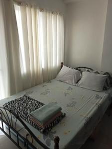 een bed in een slaapkamer met een raam met witte gordijnen bij Kassel Residences Staycation Near NAIA - Moonwalk Paranaque in Manilla