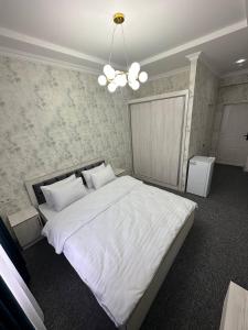 una camera da letto con un grande letto bianco e un lampadario a braccio di IMAM AZAM HOTEL a Samarkand