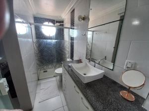 a white bathroom with a sink and a mirror at Suíte Aconchegante in Belém
