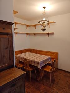uma sala de jantar com uma mesa e cadeiras e um lustre em Ciasa de Carla em Masarè