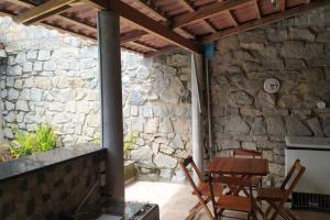 um pátio com uma mesa e cadeiras e uma parede de pedra em Casa Muro de Pedra / Cabrália em Santa Cruz Cabrália