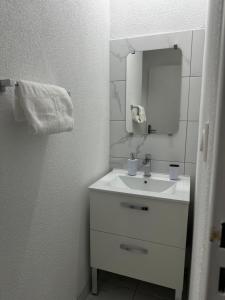 een witte badkamer met een wastafel en een spiegel bij Appartement moderne avec SPA in Essey-lès-Nancy