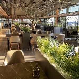 un restaurante con mesas, sillas y plantas en 01 Nova Otel, en Didim
