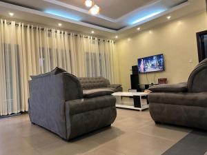 uma sala de estar com 2 cadeiras e uma televisão de ecrã plano em Cento Stalloni em Kigali