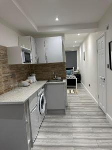 a kitchen with white cabinets and a washer and dryer at Studio flat in London in London