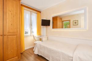 sypialnia z białym łóżkiem i lustrem w obiekcie Hotel Pontechiesa w mieście Cortina dʼAmpezzo