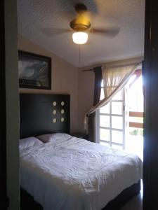a bedroom with a bed with a ceiling fan and a window at BEAUTIFUL HOME FULLY FURNISHED, READY TO RELAX AND 5 MINUTES FROM THE BEACH!! in Ixtapa