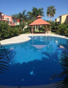 a large blue swimming pool with a gazebo at BEAUTIFUL HOME FULLY FURNISHED, READY TO RELAX AND 5 MINUTES FROM THE BEACH!! in Ixtapa