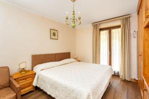 1 dormitorio con 1 cama, 1 silla y 1 ventana en Hotel Pontechiesa, en Cortina dʼAmpezzo