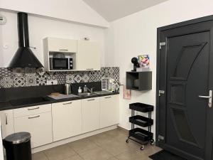 a kitchen with white cabinets and a black door at Gîte la biche des écrins in Prunières +13 photos