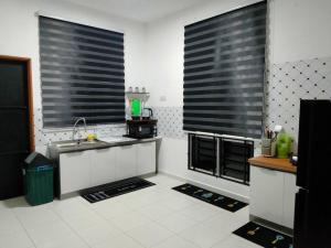 a kitchen with two large windows and a sink at Dedaun Homestay Perlis in Kangar
