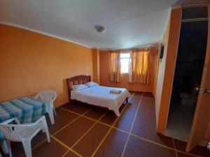 a bedroom with a bed and a table and chairs at Hotel y Restaurante Roma in Ica