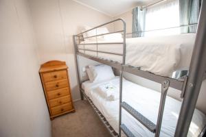 a bedroom with two bunk beds and a dresser at Sheerness Holiday Caravan for 6 in Sheerness
