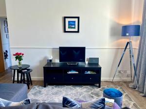 ein Wohnzimmer mit einem TV und einem schwarzen Entertainment-Center in der Unterkunft Central Apartment Linlithgow in Linlithgow