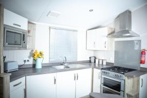 a kitchen with white cabinets and a stove at Sheerness Holiday Caravan for 6 in Sheerness